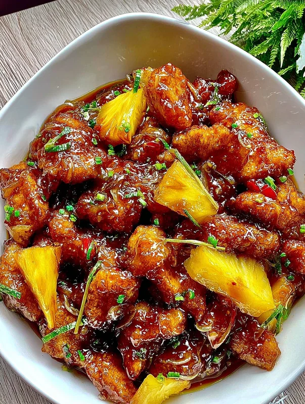 Sliced brown sugar pineapple chicken served over steamed white rice with sauce